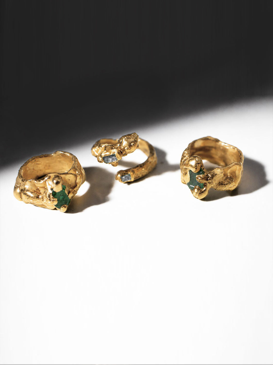 Three gold rings with embedded emerald stones on a white background - The Bow Jewelry