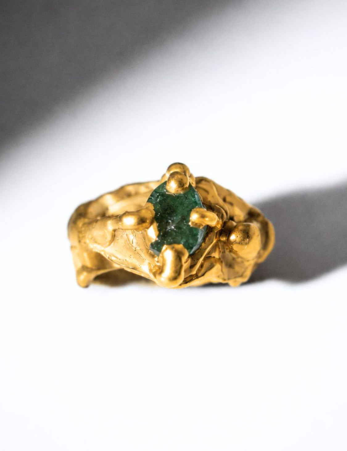Gold ring with a emerald gemstone on a white background - The Bow Jewelry