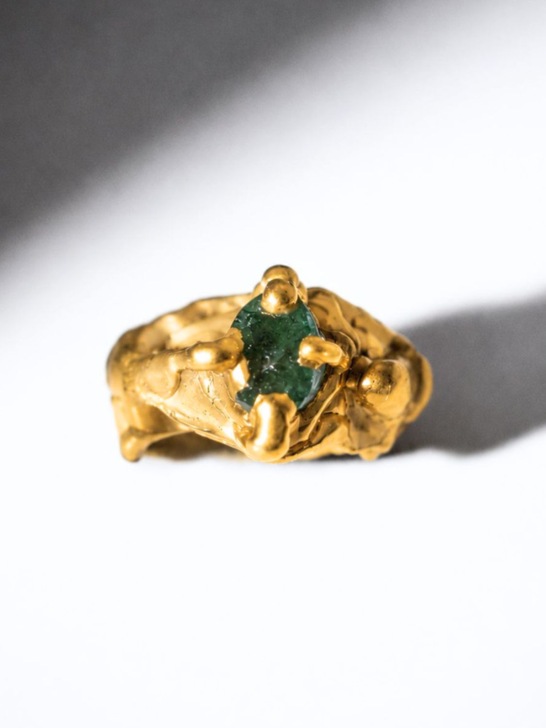 Gold ring with a emerald gemstone on a white background - The Bow Jewelry