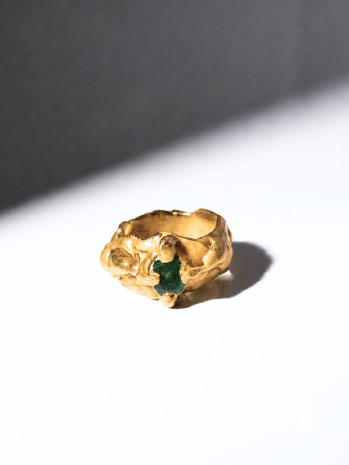 Gold ring with a emerald gemstone on a white background - The Bow Jewelry