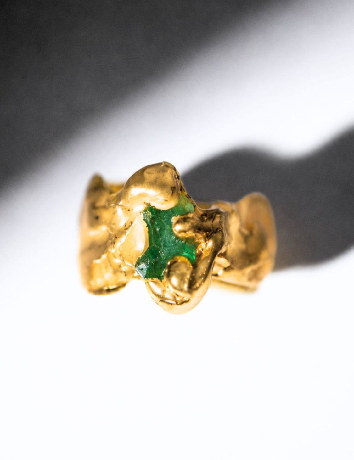 Gold ring with a emerald gemstone on a white background - The Bow Jewelry