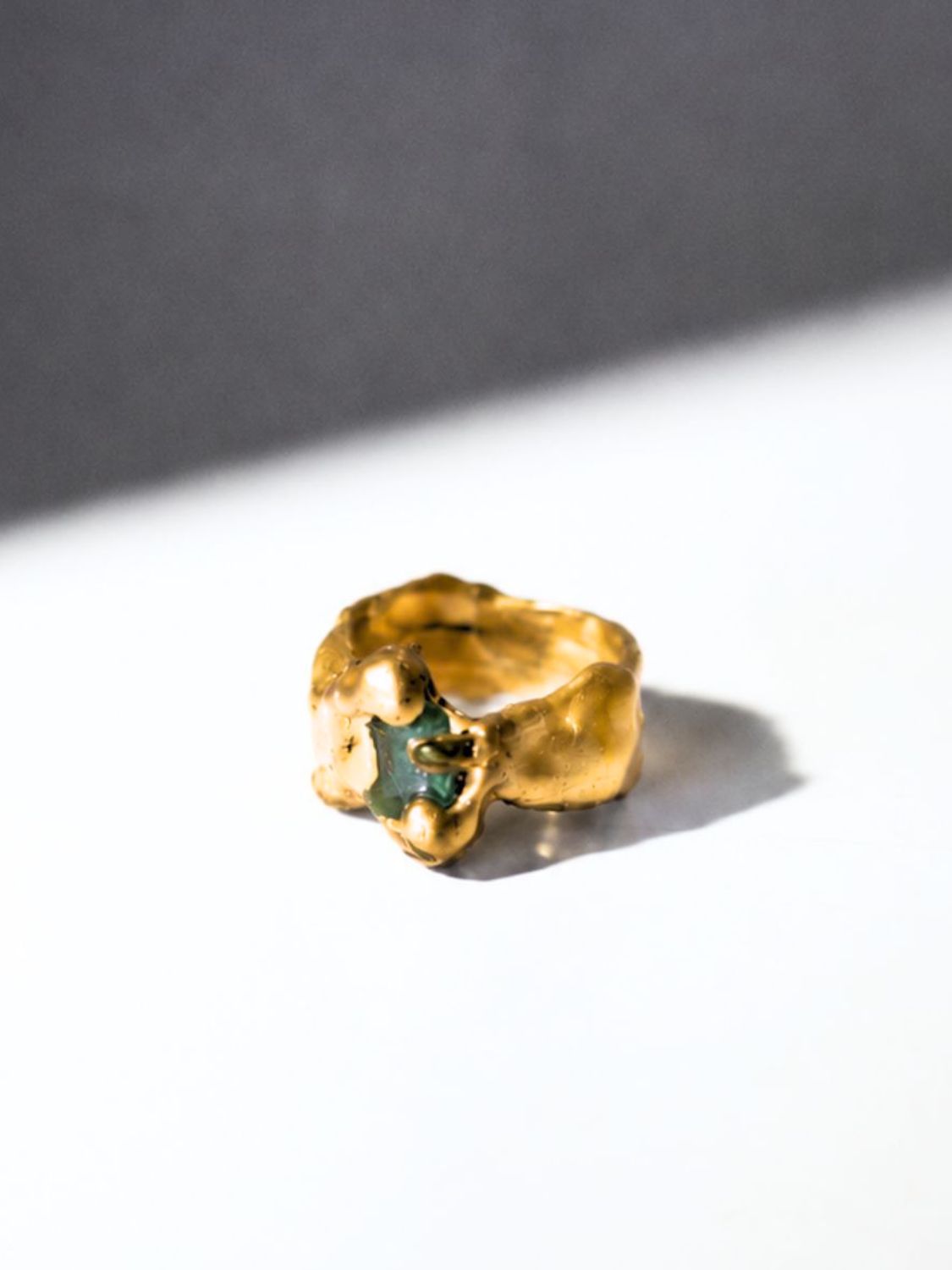 Gold ring with a emerald gemstone on a white background - The Bow Jewelry