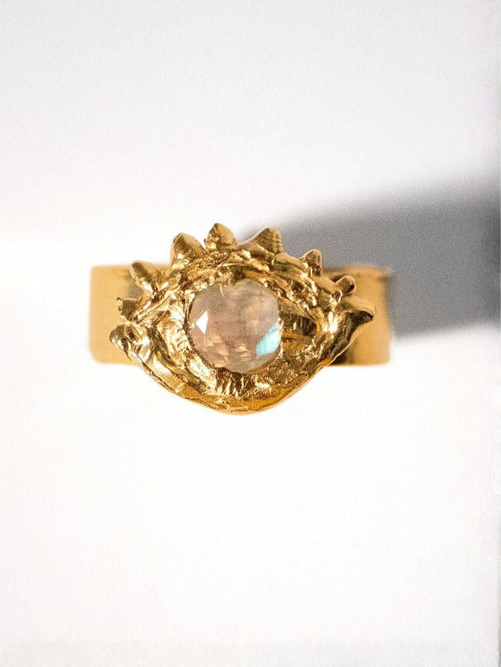 Gold ring with a central gemstone on an eye shape and white background