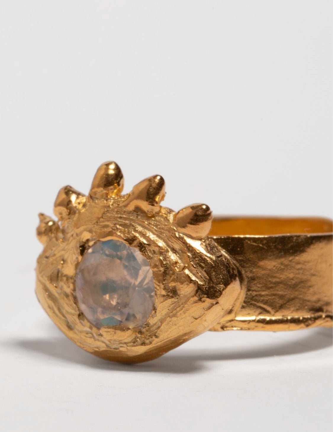 Gold ring with a central gemstone on an eye shape and white background