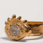 Gold ring with a central gemstone on an eye shape and white background