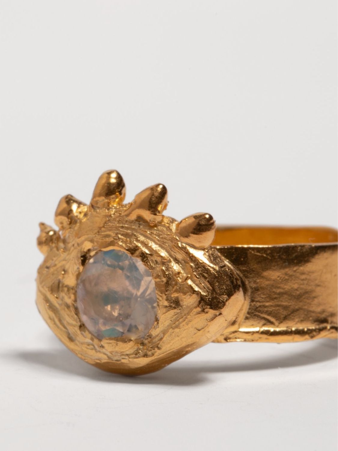 Gold ring with a central gemstone on an eye shape and white background