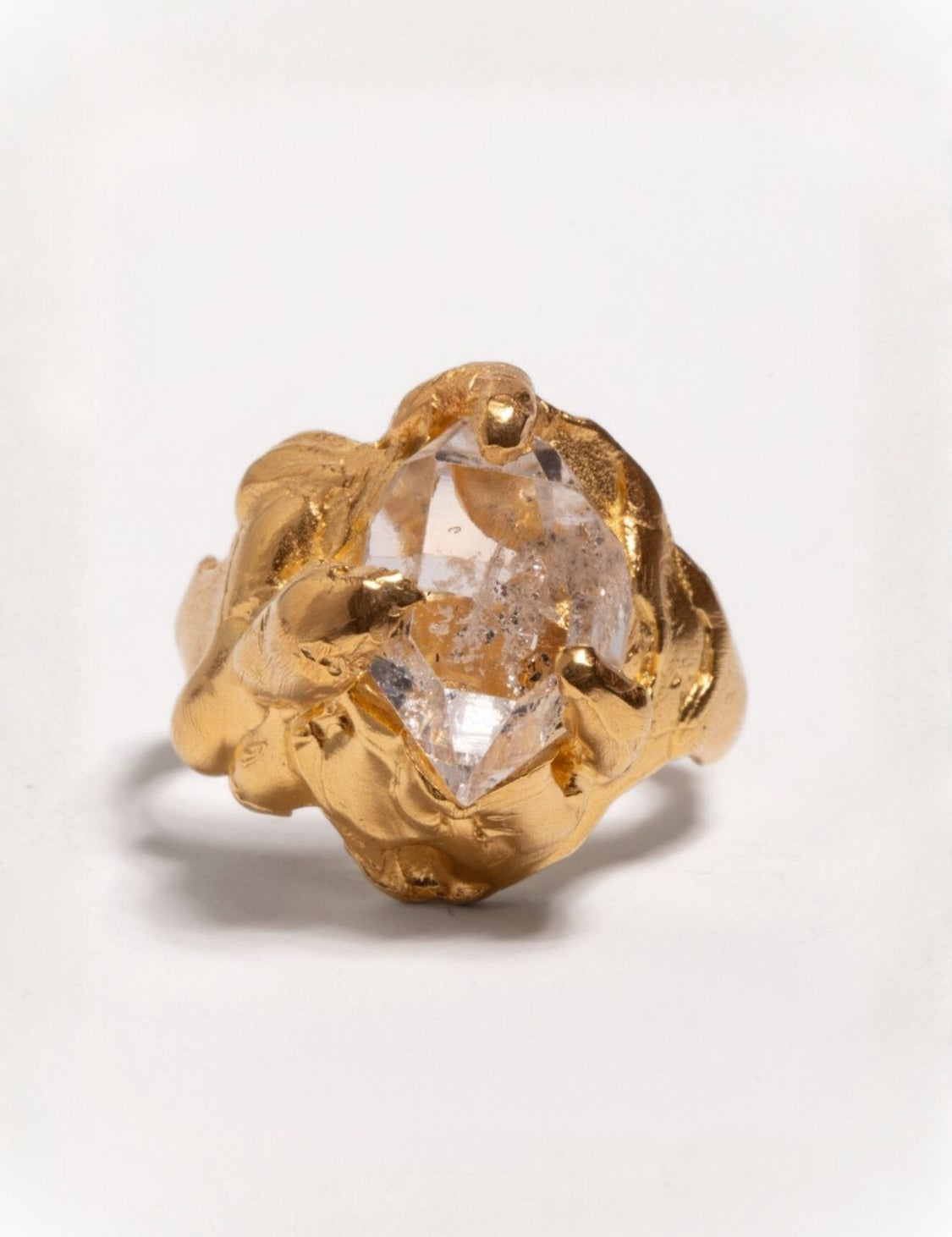 Gold ring with a herkimer quartz gemstone on a light gray background