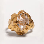 Gold ring with a herkimer quartz gemstone on a light gray background