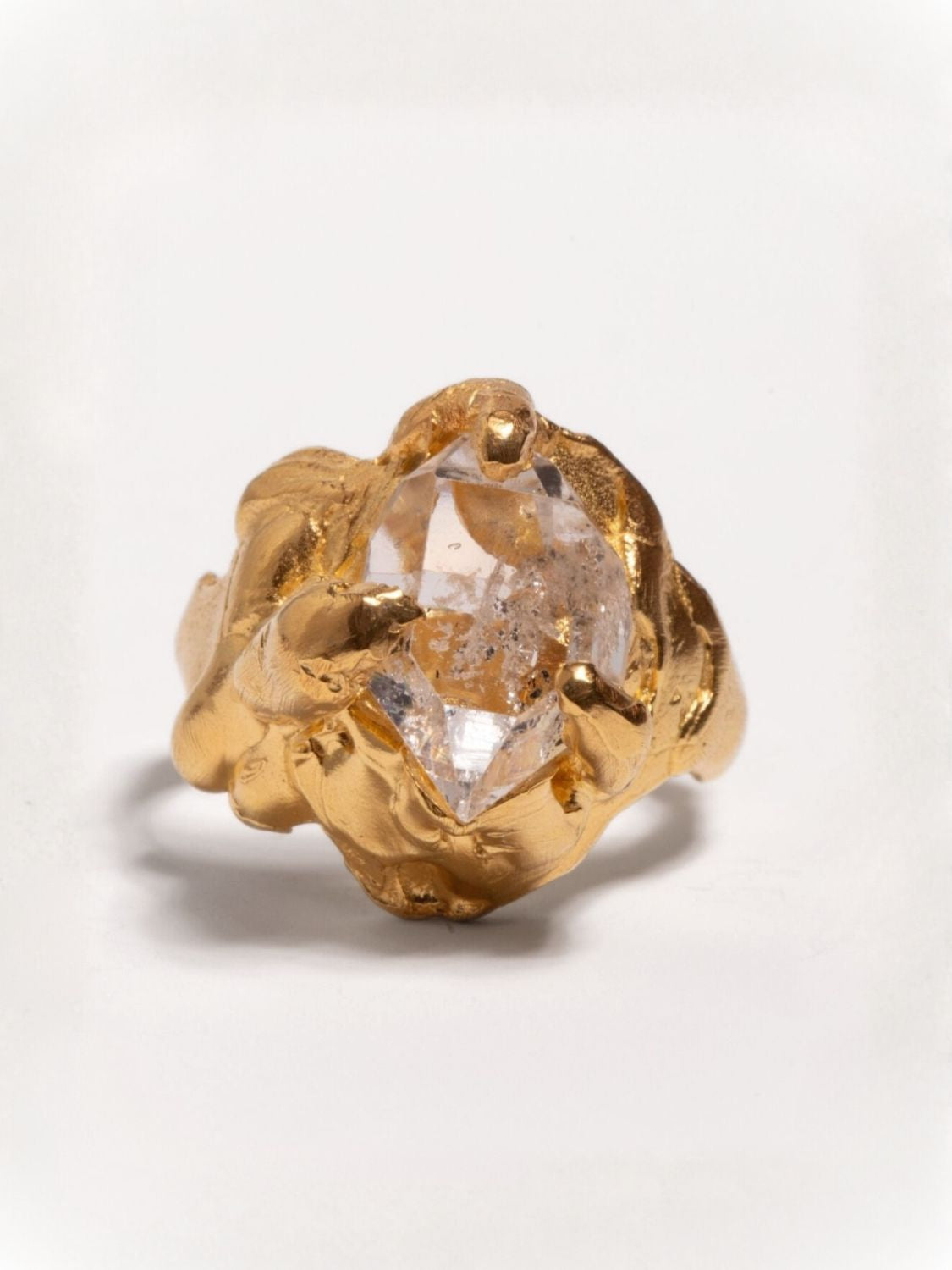 Gold ring with a herkimer quartz gemstone on a light gray background