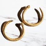 Gold Serpent Ouroboros hoop earrings on a white marble surface | The Bow Jewelry