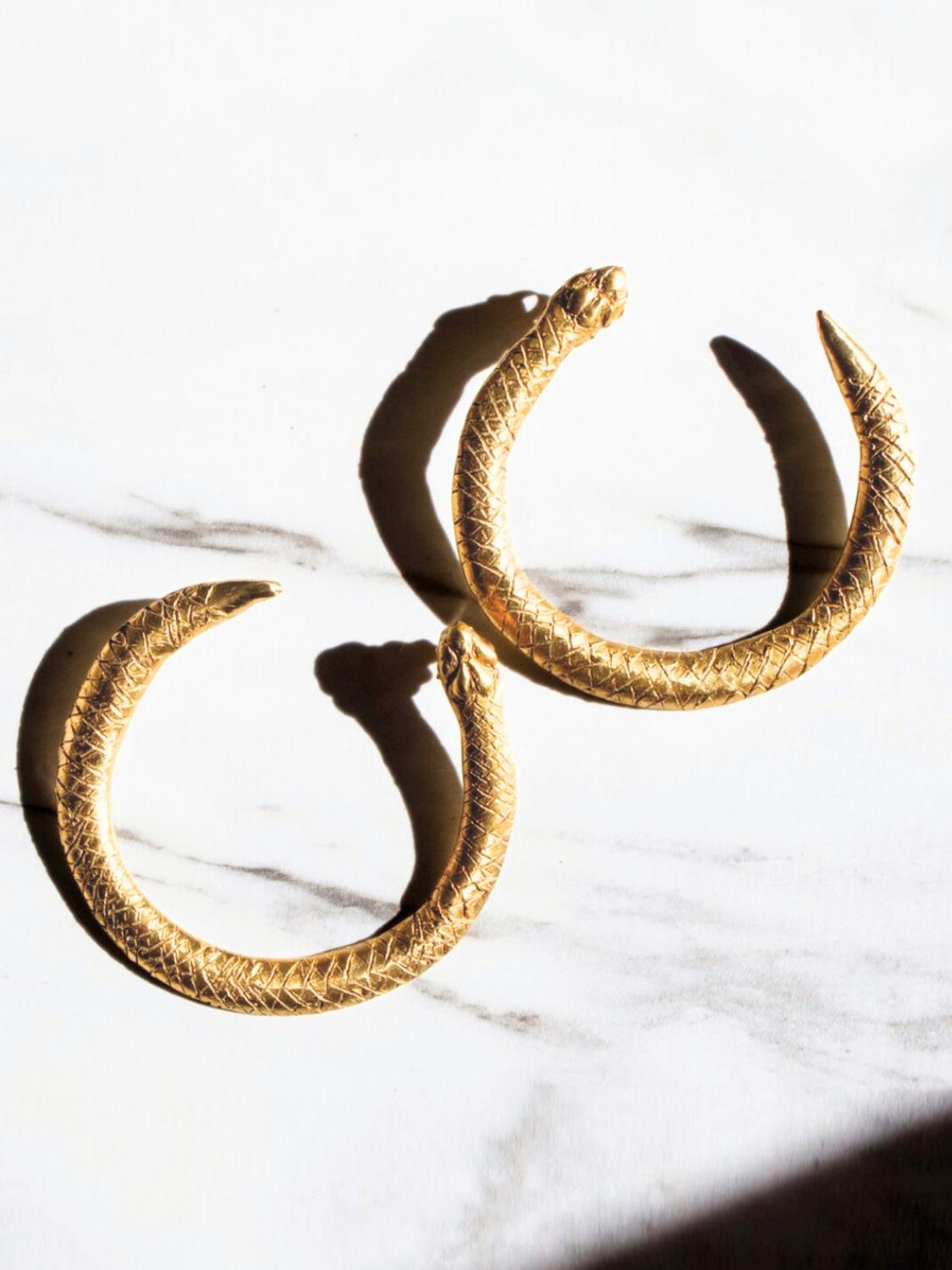 Gold Serpent Ouroboros hoop earrings on a white marble surface | The Bow Jewelry