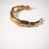 Gold sculptural hoops on a light grey background