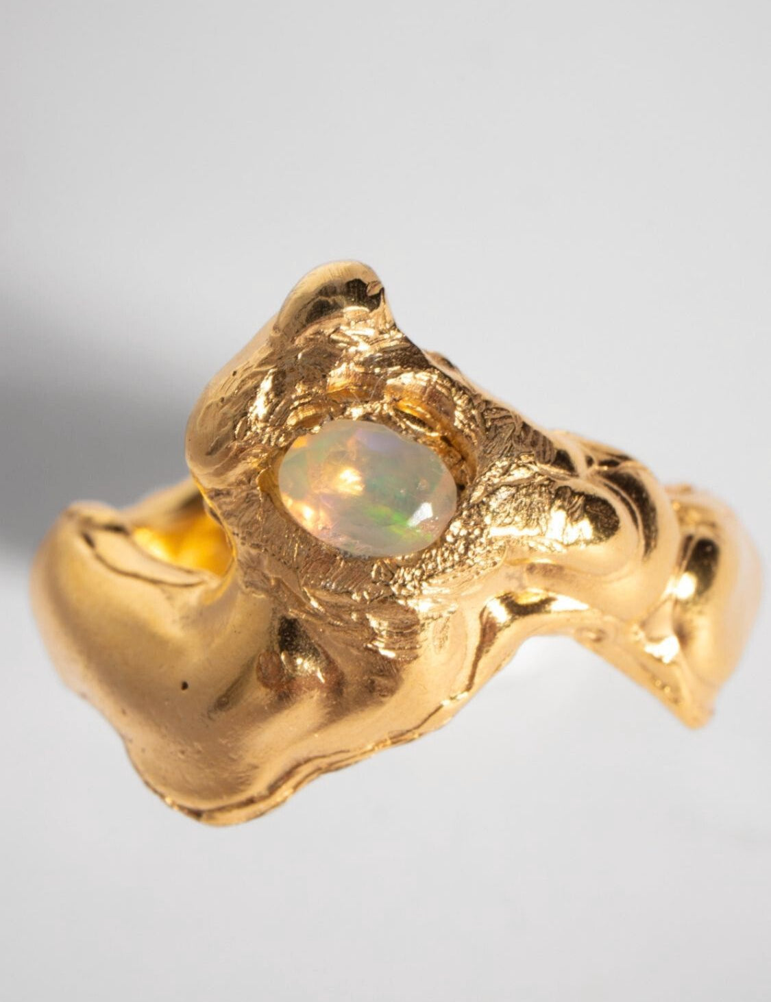 A gold-plated band ring with a faceted natural fire opal gemstone set in the center, displayed on a plain background | The Bow Jewelry