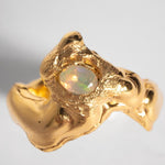 A gold-plated band ring with a faceted natural fire opal gemstone set in the center, displayed on a plain background | The Bow Jewelry