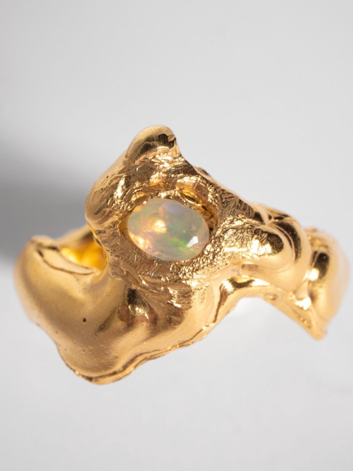 A gold-plated band ring with a faceted natural fire opal gemstone set in the center, displayed on a plain background | The Bow Jewelry