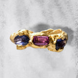 Gold ring with multicolored gemstones on a textured gray background