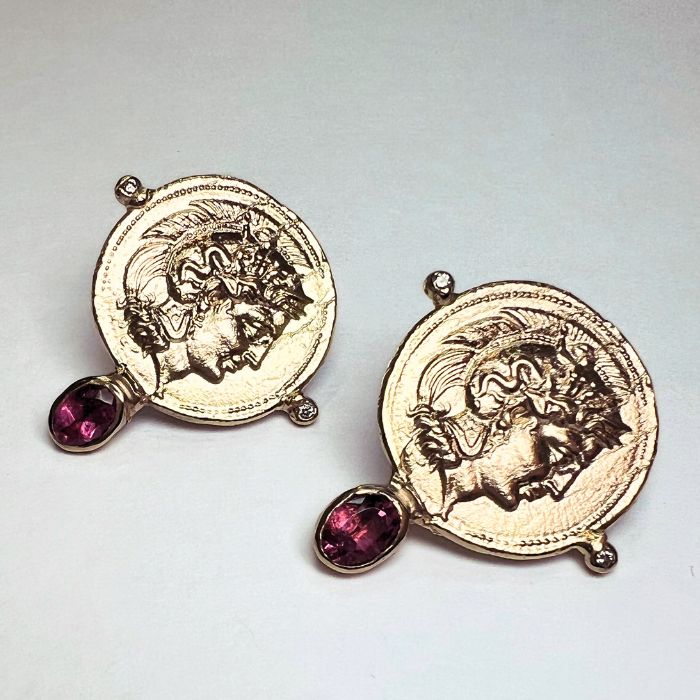 Pair of gold earrings with gemstone drops on a light gray background