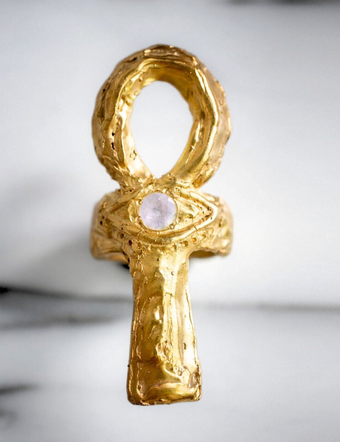 Gold ankh pendant with a central gemstone on a light background | The Bow Jewelry