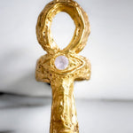 Gold ankh pendant with a central gemstone on a light background | The Bow Jewelry