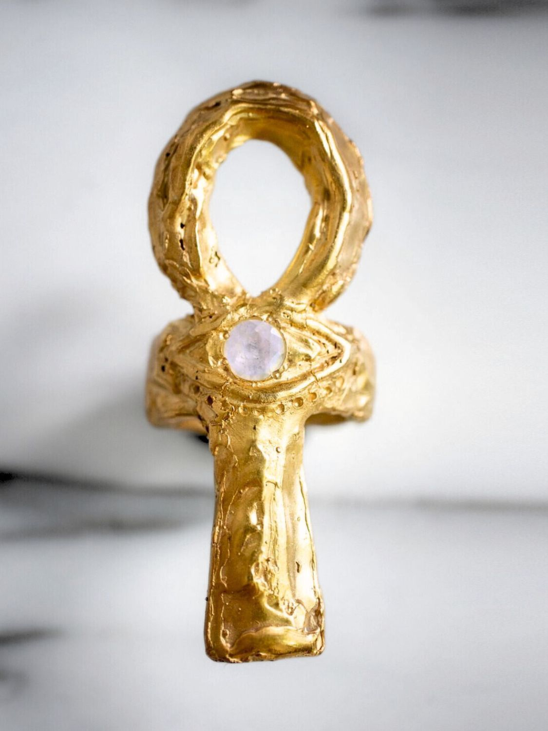 Gold ankh pendant with a central gemstone on a light background | The Bow Jewelry