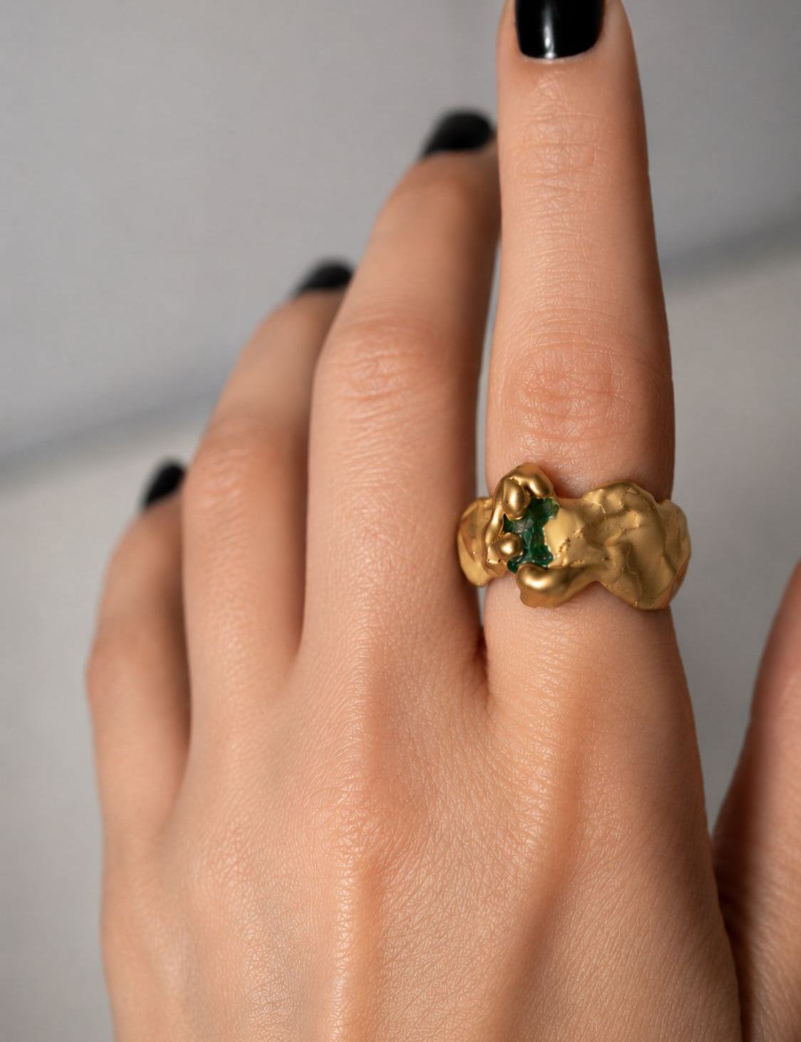 Gold ring with a emerald gemstone on a hand - The Bow Jewelry
