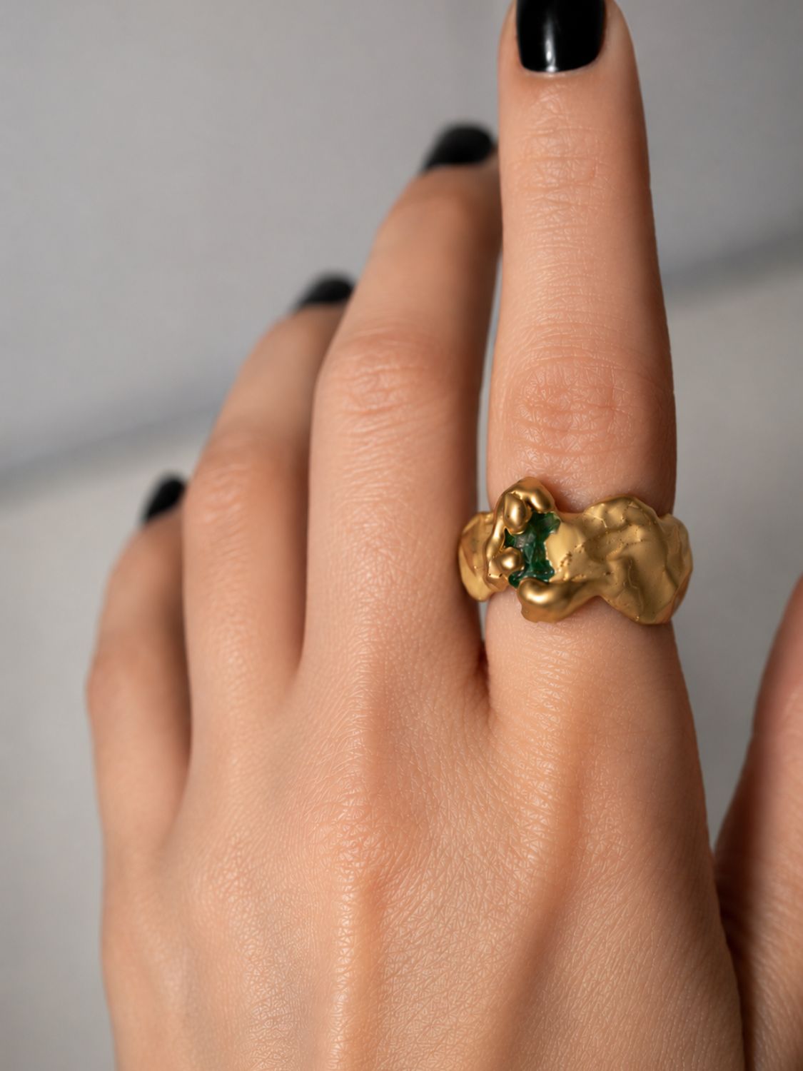 Gold ring with a emerald gemstone on a hand - The Bow Jewelry
