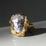 Gold ring with a large pearl on a dark surface