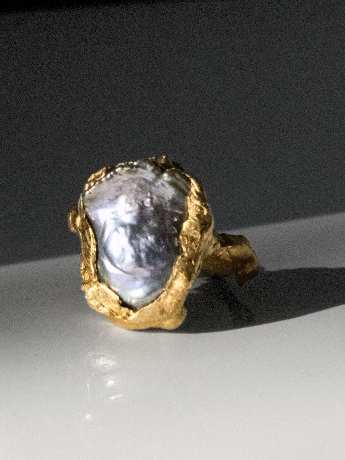 Gold ring with a large pearl on a dark surface