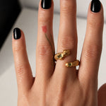 Gold snake shaped ring with two emerald gemstones on a hand - The Bow Jewelry
