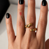 Gold snake shaped ring with two emerald gemstones on a hand - The Bow Jewelry