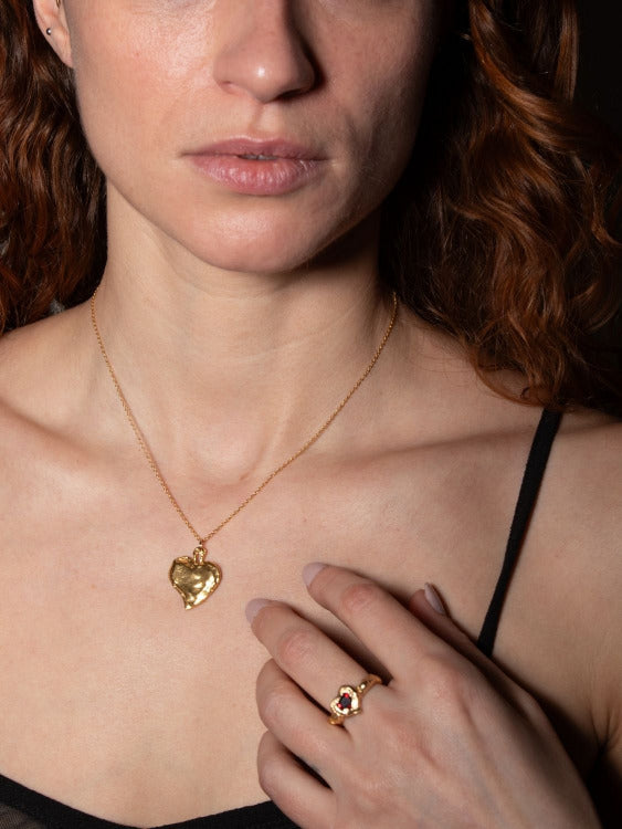 A model wearing gold-plated Heart shaped ring with a pear-shaped garnet in the center, set in a heart shape | The Bow Jewelry