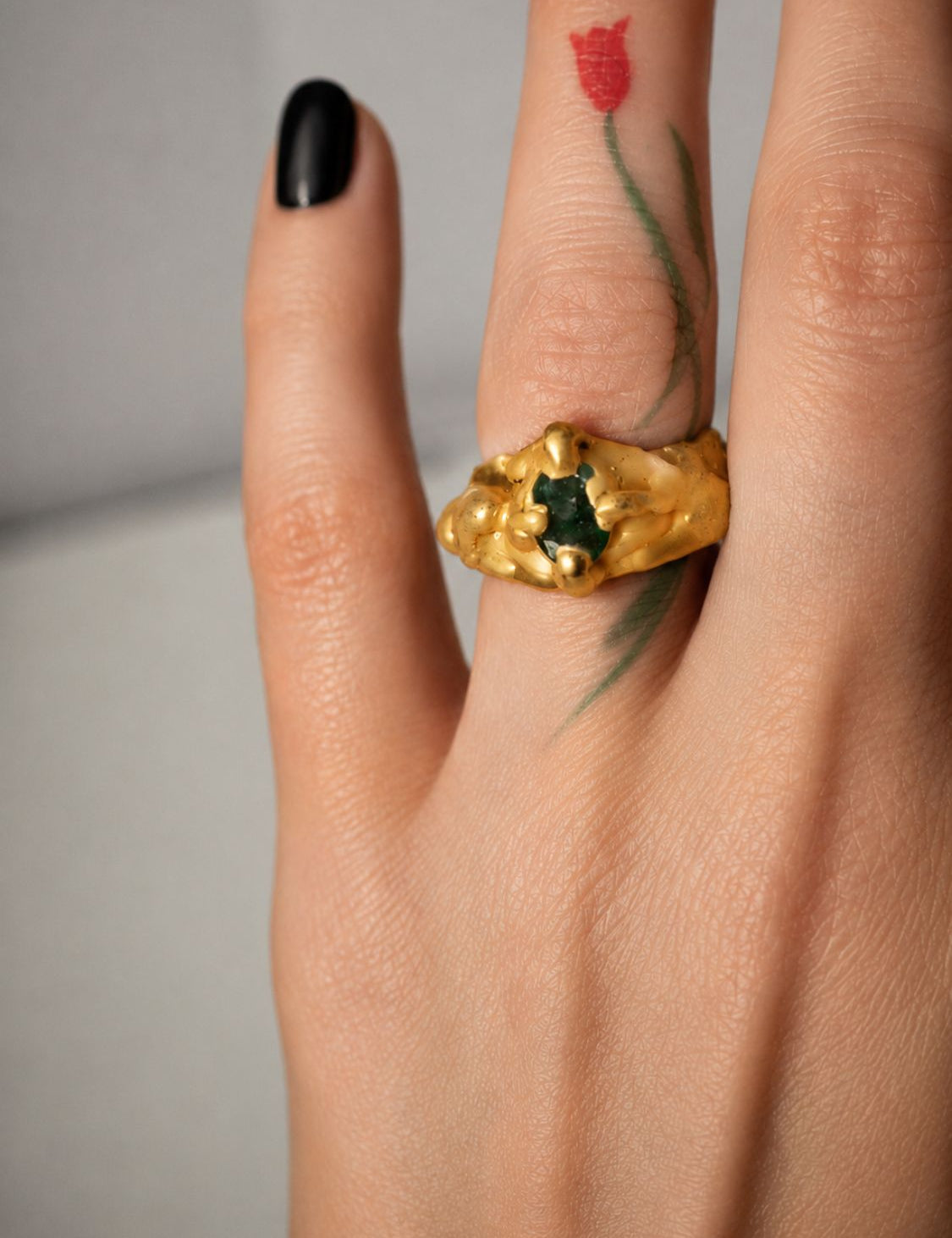 Gold ring with an oval emerald gemstone on a hand - The Bow Jewelry