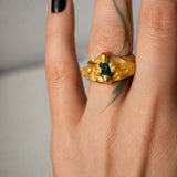 Gold ring with an oval emerald gemstone on a hand - The Bow Jewelry