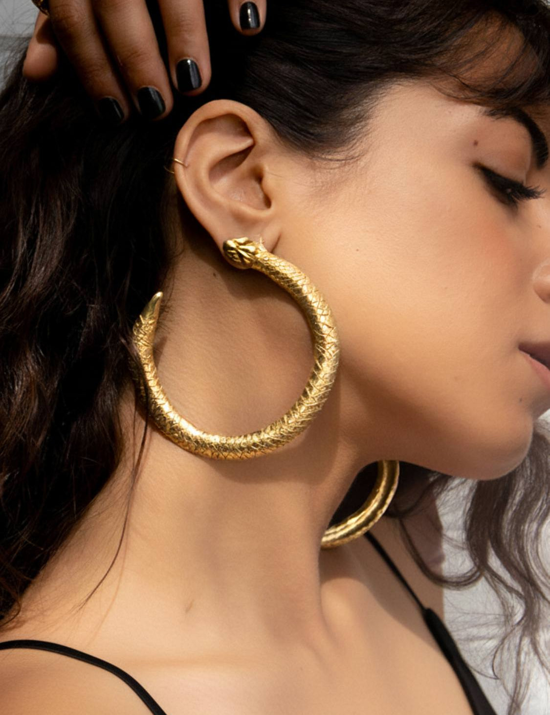 Gold Serpent Ouroboros hoop earrings on a white marble surface | The Bow Jewelry