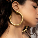 Gold Serpent Ouroboros hoop earrings on a white marble surface | The Bow Jewelry