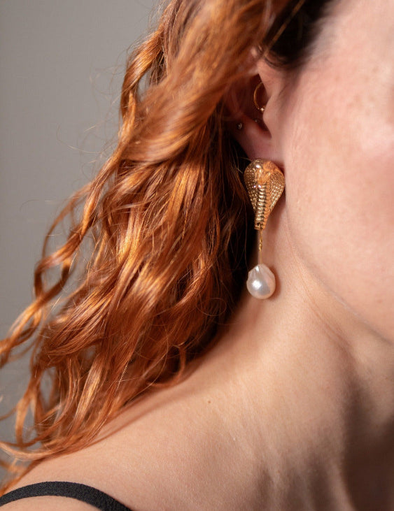 A pair of gold-plated brass earrings featuring baroque pearls and a cobra design on model | The Bow Jewelry
