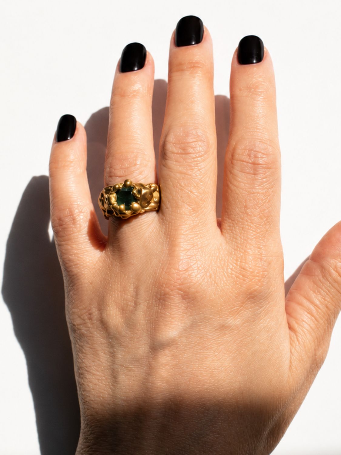 Gold ring with a emerald gemstone on a hand - The Bow Jewelry