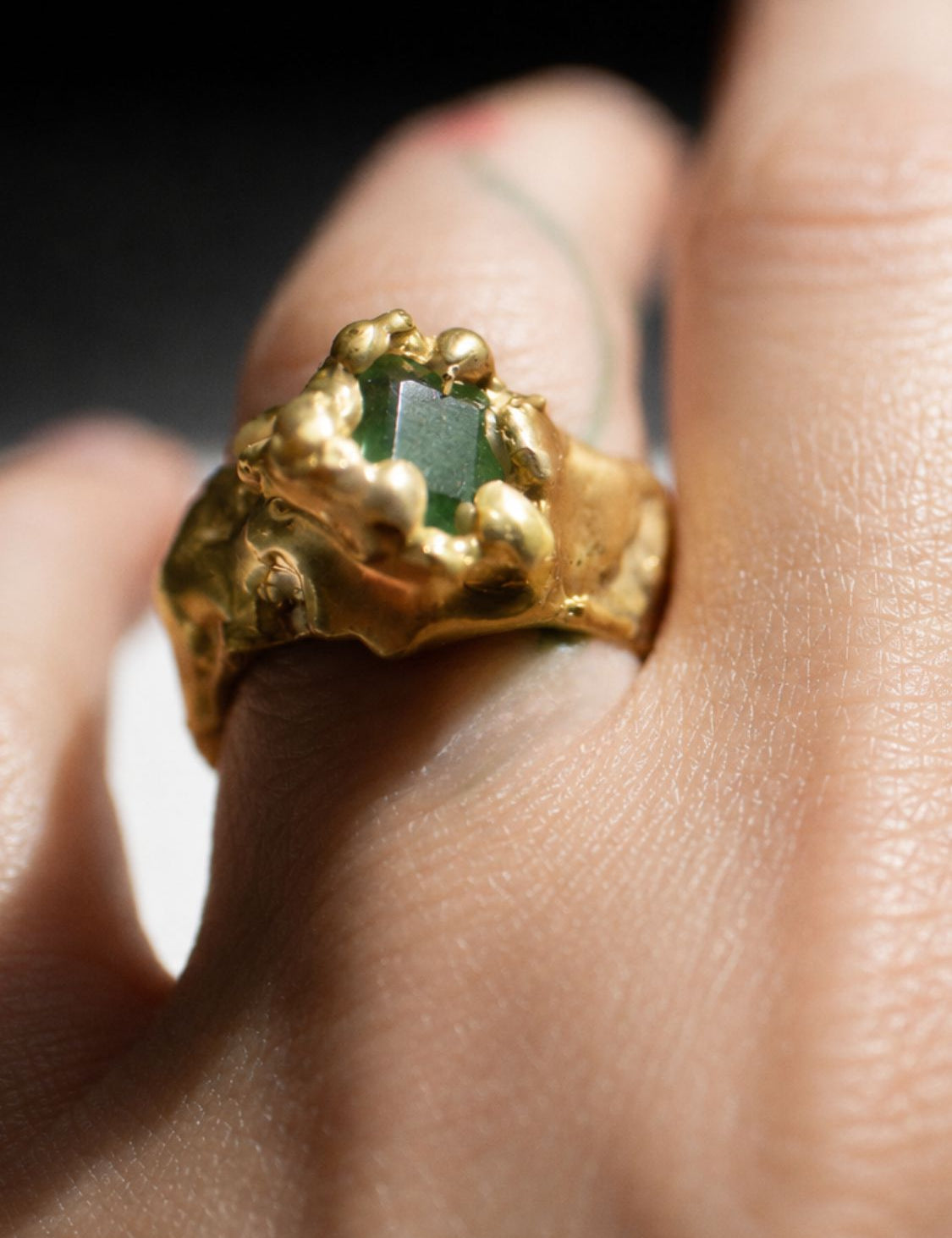 Gold ring with a emerald gemstone on a hand - The Bow Jewelry