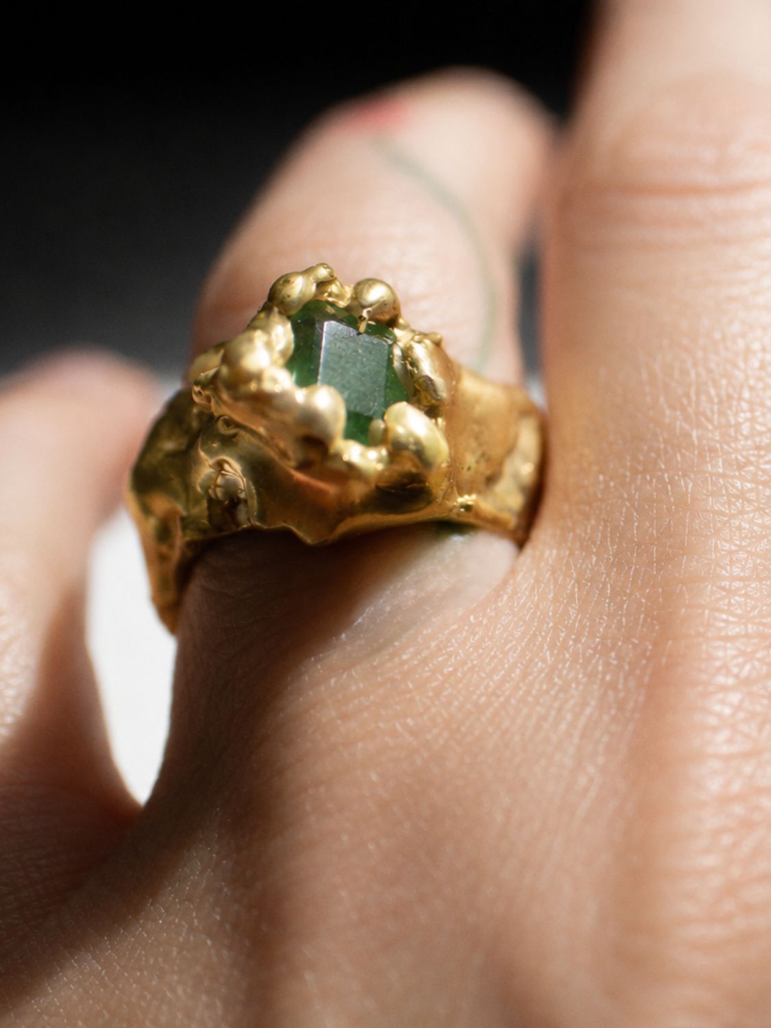Gold ring with a emerald gemstone on a hand - The Bow Jewelry
