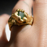 Gold ring with a emerald gemstone on a hand - The Bow Jewelry