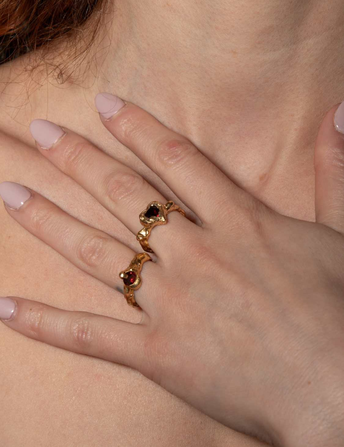 A model wearing gold-plated Heart shaped ring with a pear-shaped garnet in the center, set in a heart shape | The Bow Jewelry
