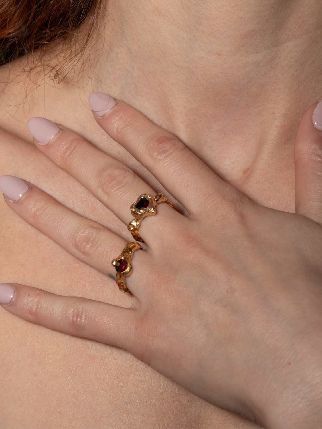 A model wearing gold-plated Heart shaped ring with a pear-shaped garnet in the center, set in a heart shape | The Bow Jewelry
