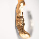 Gold goddess-shaped earring on a light grey background