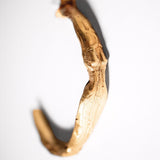 Gold-colored sculptural goddess hoops on a white background