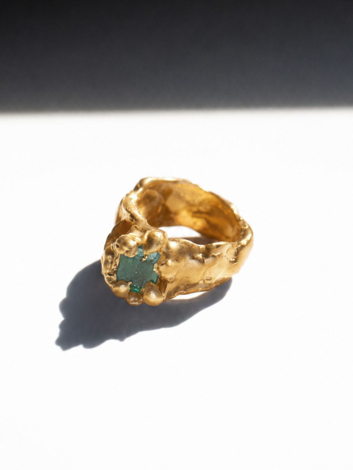 Gold ring with a emerald gemstone on a white background - The Bow Jewelry